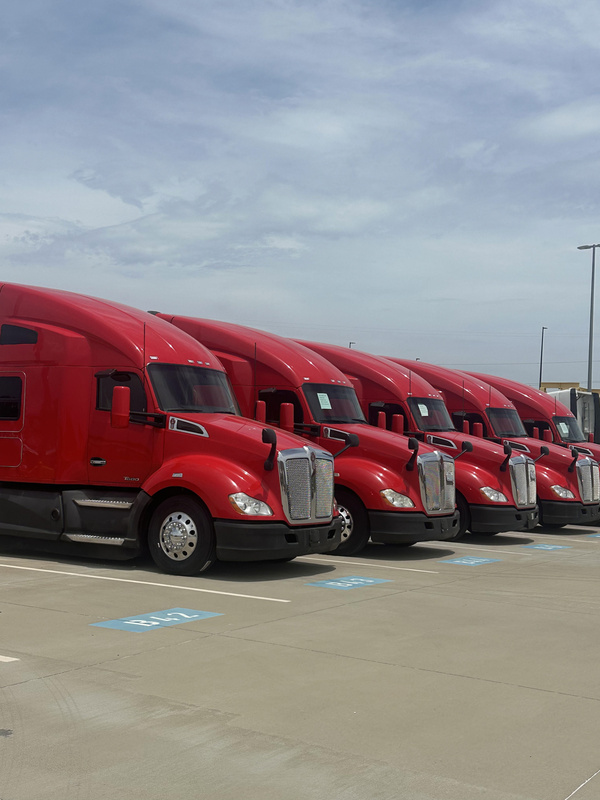 A lineup of red semi trucks, pictured in the Green Pilot Enterprises capabilities statement
